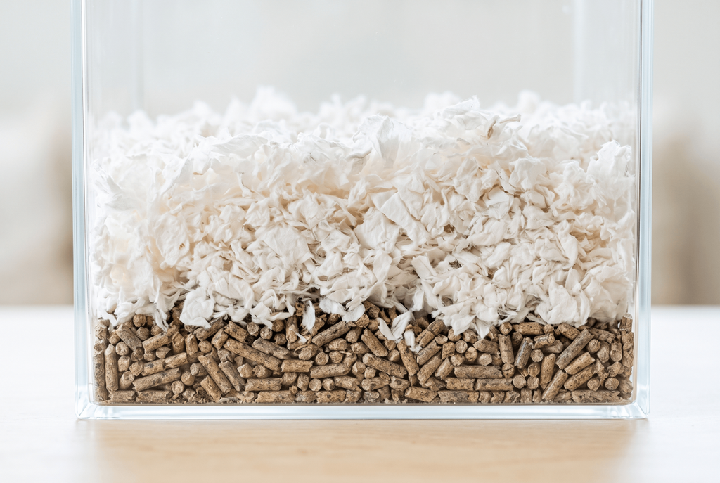 Pellets used as a base layer under soft paper bedding